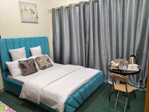 a bedroom with a bed with a blue headboard and a table at GRACE BEDSPACE, HOSTEL AND ACCOMODATIONS in Dubai