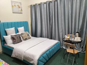 - une chambre avec un lit doté d'une tête de lit bleue et d'une table dans l'établissement GRACE BEDSPACE, HOSTEL AND ACCOMODATIONS, à Dubaï