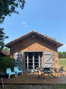 um pátio com uma mesa e cadeiras num deque em Domaine Au Bon em Angresse