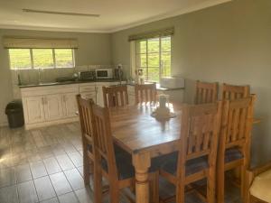 a kitchen with a wooden table and wooden chairs at Mountain View Farm Cottage 4X4 Vehicles ONLY in Dullstroom