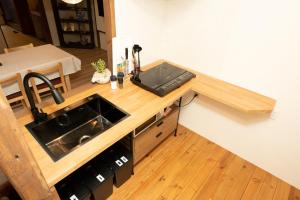 - une cuisine avec un évier et un comptoir en bois dans l'établissement つばめ荘 Tsubamesou, à Onomichi