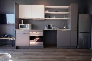 La cuisine est équipée de placards blancs, d'une cuisinière et d'un réfrigérateur. dans l'établissement Modern Studio in Wex1 538, au Cap