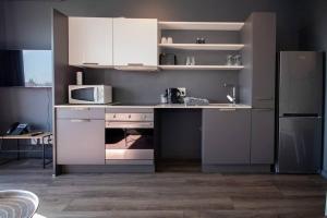 cocina con armarios blancos, fogones y nevera en Modern Studio in Wex1 538, en Ciudad del Cabo