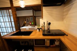 encimera de cocina con fregadero y microondas en つばめ荘 Tsubamesou en Onomichi
