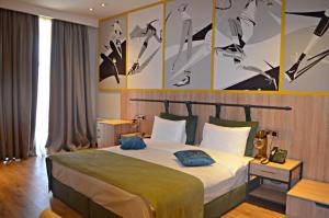 a bedroom with a large bed with paintings on the wall at Arena Sport Hotel in Quba
