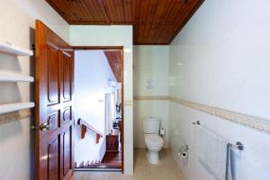 a bathroom with a toilet and a wooden door at Chalets Cote Mer in Baie Sainte Anne