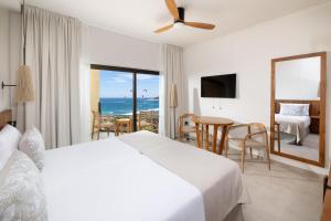 Hotel Playa Sur Tenerife في إل ميدانو: غرفة نوم مع سرير وإطلالة على المحيط