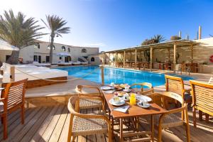 um pátio com uma mesa e cadeiras ao lado de uma piscina em Hotel Playa Sur Tenerife em El Médano