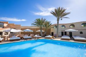 ein großer Pool mit Stühlen und Sonnenschirmen in der Unterkunft Hotel Playa Sur Tenerife in El Médano