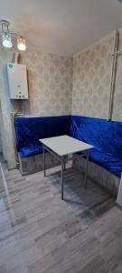Habitación con mesa y sofá azul en 2-комнатная квартира, 55 м², 2/5 этаж посуточно, 8-й микрорайон, 8-й микрорайон 16, en Shymkent