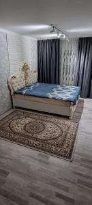 1 dormitorio con 1 cama y 1 alfombra en una habitación en 2-комнатная квартира, 55 м², 2/5 этаж посуточно, 8-й микрорайон, 8-й микрорайон 16, en Shymkent