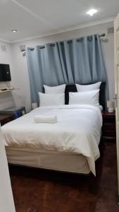 a bedroom with a large white bed with a blue headboard at Suprime Hotels and Conference in Pietermaritzburg
