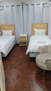 Habitación con 2 camas, silla y sofá en Suprime Hotels and Conference, en Pietermaritzburg