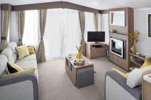 a living room with a couch and a tv at Polladras Holiday Park in Helston