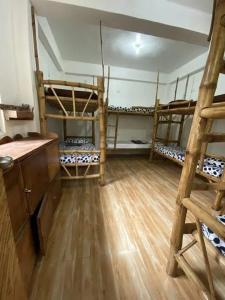 a room with three bunk beds and a wooden floor at Georgia's Neverland Hostel in Malapascua Island