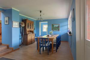 een eetkamer met blauwe muren en een tafel en stoelen bij Viesu māja Vanaturs in Roja