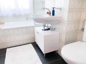 uma casa de banho branca com um lavatório e um WC em Bündapark em Davos