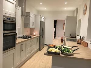 eine Küche mit einer Theke mit Schalen mit Gemüse darauf in der Unterkunft Modern 4 bed house near city centre/Chester Zoo in Chester