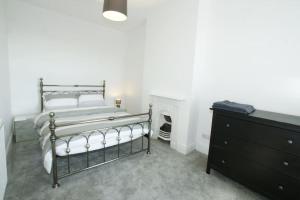 a bedroom with a bed and a dresser and a fireplace at Modern 4 bed house near city centre/Chester Zoo in Chester