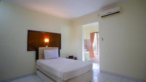 a bedroom with a white bed in a room at Teges Inn Kuta in Kuta