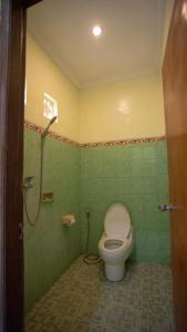 a bathroom with a toilet and a shower in it at Teges Inn Kuta in Kuta