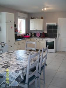 una cocina con mesa y sillas y una cocina con armarios blancos. en Le Gîte du Doulac, en Saint-Omer