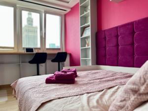 um quarto rosa com uma cama grande e uma cabeceira roxa em -- View City Center Pink -- em Varsóvia