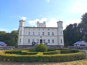 a large white house with hedges in front of it at Pałac Lubiechowo in Lubiechowo