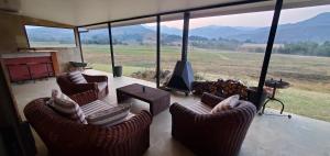 a living room with chairs and a flat screen tv at Aspen Villa Misty Mountain Studio in Underberg