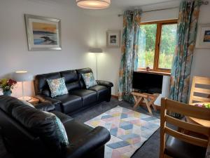 ein Wohnzimmer mit einem Ledersofa und einem TV in der Unterkunft Birch Lodge in Fort William