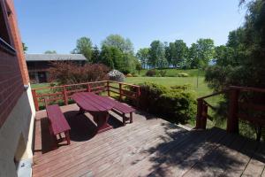 a wooden deck with a picnic table and a fence at Viesu māja Vanaturs in Roja