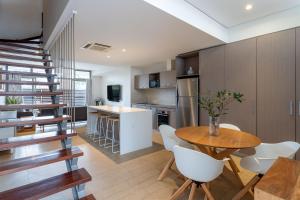 a kitchen and dining room with a wooden table and white chairs at Dunn Bay Apartment 5 - Dunsborough in Dunsborough