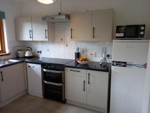 a kitchen with white appliances and a bowl of fruit on the counter at Birch Lodge in Fort William