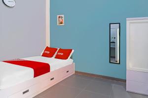 um quarto com uma cama com almofadas vermelhas em OYO Life 92691 Mc Kost Syariah em Jambi