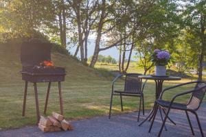 a grill and two chairs and a table with a fire at Apartment-A near Etne-Odda in Etnesjøen