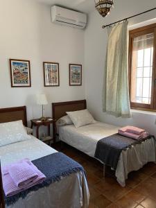 a bedroom with two beds and a window at Casa Rural La Joyona in Los Navalucillos