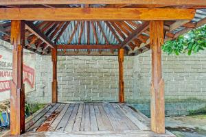 a wooden covered porch with a brick wall at OYO Life 93058 Kos Subur in Tanjung