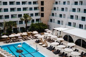 una piscina con sedie a sdraio e ombrelloni accanto a un hotel di Neve Eilat Hotel Former Nova By Atlas Hotels a Eilat