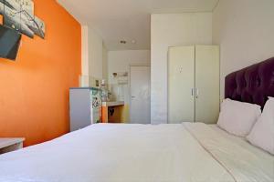 een slaapkamer met een wit bed en een oranje muur bij OYO Life 92898 Apartement Buah Batu Park By Yuliam in Bandung