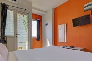 een slaapkamer met oranje muren en een bed en een raam bij OYO Life 92898 Apartement Buah Batu Park By Yuliam in Bandung