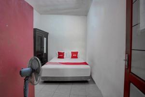 een slaapkamer met een bed met rode kussens erop bij OYO Life 92840 Wisma Morricco in Jombang