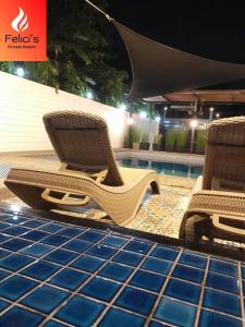 two chairs sitting next to a swimming pool at night at Felici's Private Resort in Los Baños
