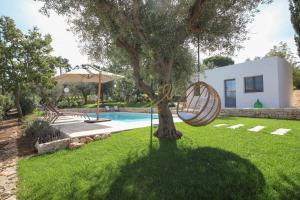ein Baum in einem Garten neben einem Pool in der Unterkunft Trulli Dimore - Tortorella in Monopoli