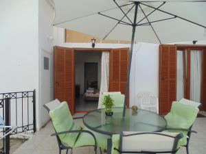 a glass table and chairs with an umbrella at Maria Studios in Skiathos