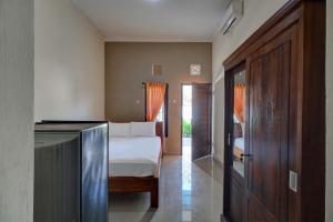 ein Schlafzimmer mit einem Bett und einer Tür zu einem Zimmer in der Unterkunft OYO Life 92838 Kost Ibu Surya in Negara
