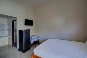 um quarto com uma cama e uma televisão na parede em OYO Life 92838 Kost Ibu Surya em Negara