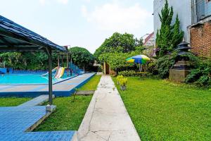 een tuin met een zwembad met een parasol bij OYO Life 92835 Maya Adipuri in Bandung