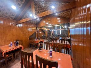 restauracja z drewnianymi ścianami, stołami i krzesłami w obiekcie Pine View Resort w mieście Gulmarg
