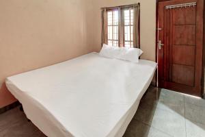 een groot wit bed in een kamer met een deur bij OYO Life 92846 Kost Putra Griya Eka in Tanjungkarang