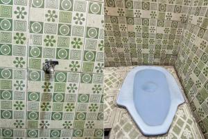 een toilet in een badkamer met groene en witte tegels bij OYO Life 92846 Kost Putra Griya Eka in Tanjungkarang